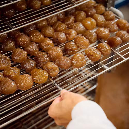 Égouttage artisanal des marrons confits dans l'atelier